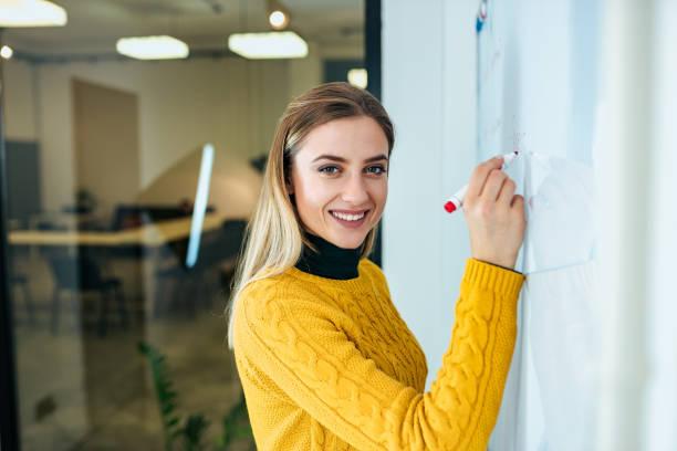 istock Young businesswoman writing on white board. Looking at camera. 1069584676