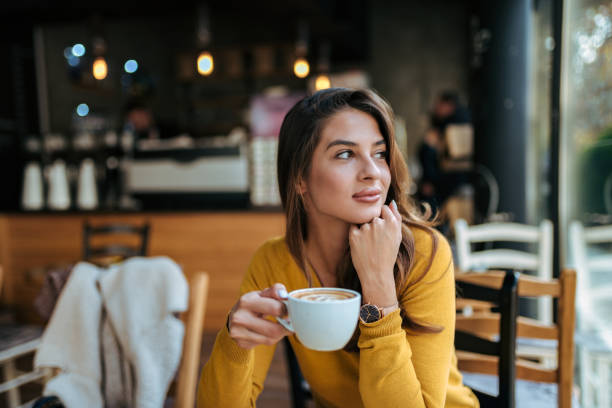 stylish young woman drinking coffee at the cafe, looking away. - cafe bar imagens e fotografias de stock