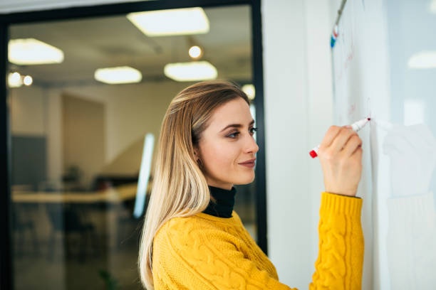 istock Young casual businesswoman working against white board. 1069585070