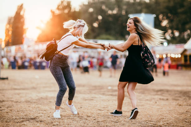 Friends having fun Two female friends spinning around and having fun at music festival music festival stock pictures, royalty-free photos & images