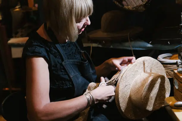 Milliner making handmade customized hats in her workshop.