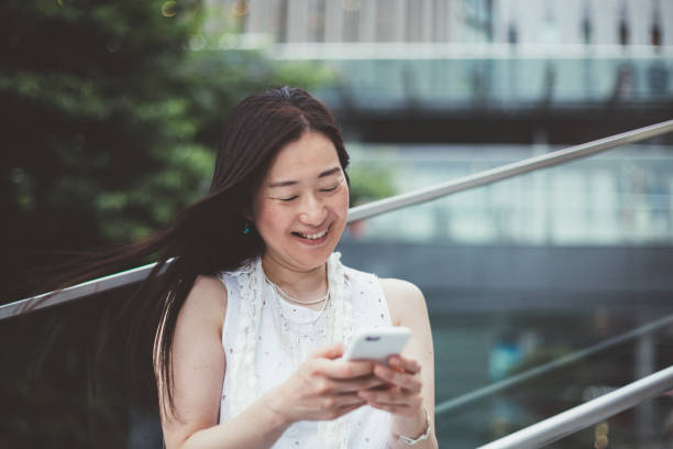 istock Japanese businesswoman texting outside 1069593988
