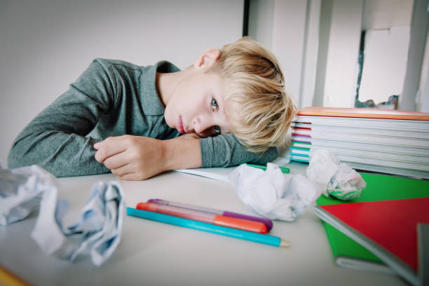 istock little boy tired stressed of reading, doing homework 1069594186