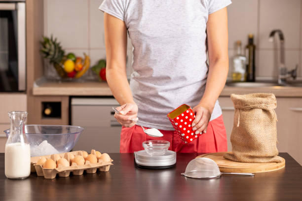 istock Woman measuring sugar on kitchen measuring scale 1069595760
