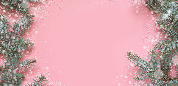 Christmas frame made of fir branches, festive white decor on pink table. Xmas background. Flat lay. Top view with copy space