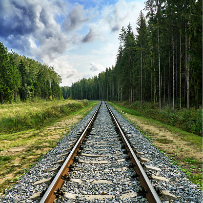 Summer railway view with forest and cloudy blue sky in Russia