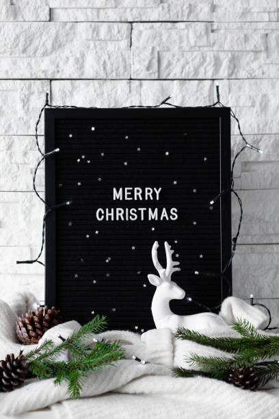 istock Black board with Merry Christmas message stay on the table with Christmas decoration on white brick wall background 1069598230