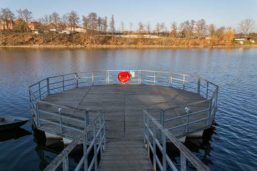 Red lifebuoy hanging on wooden pier, Jordan pond, Tabor, oldest dam in the Czech Republic, sunny autumn day, life insurance concept