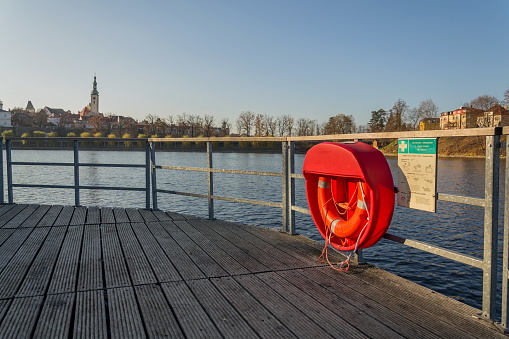 Red lifebuoy hanging on wooden pier, Jordan pond, Tabor, oldest dam in the Czech Republic, sunny autumn day, life insurance concept