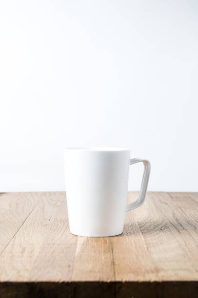 istock White mug on a wooden table. Template for text or design 1069604124
