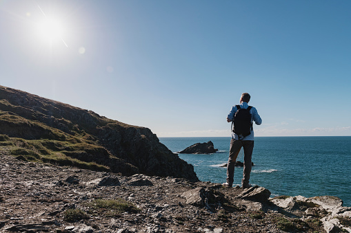 a man walking the Cornish coast in Autumn sunshine stopped to look at the view.