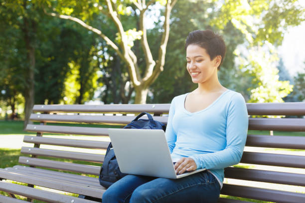 istock Young woman using laptop sitting outdoors 1069609728