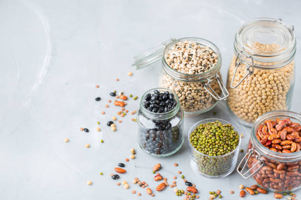 Assortment of vegan protein source food, legumes, lentils, chickpeas, beans Healthy food, dieting, nutrition concept, vegan protein source. Assortment of colorful legumes in jars, lentils, soy kidney beans, chickpeas on a modern kitchen table. Copy space background legume family stock pictures, royalty-free photos & images