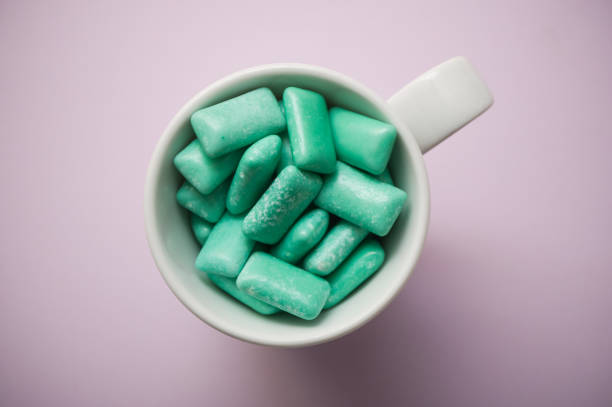 istock peppermint chewing gum in a white cup on purple background 1069617066