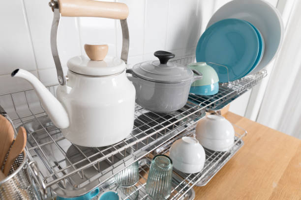 istock Clean dishes drying on metal dish rack on light background. Kitchen utensils and dishware on wooden shelf. Kitchen interior background.Text space. 1069621834