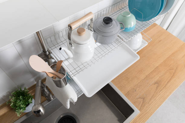 istock Clean dishes drying on metal dish rack on light background. Kitchen utensils and dishware on wooden shelf. Kitchen interior background.Text space. 1069622012