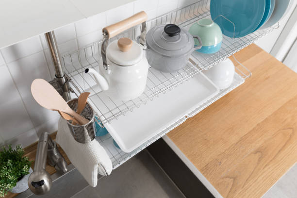 istock Clean dishes drying on metal dish rack on light background. Kitchen utensils and dishware on wooden shelf. Kitchen interior background.Text space. 1069622014