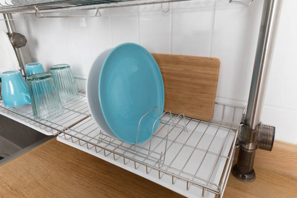istock Clean dishes drying on metal dish rack on light background. Kitchen utensils and dishware on wooden shelf. Kitchen interior background.Text space. 1069622080