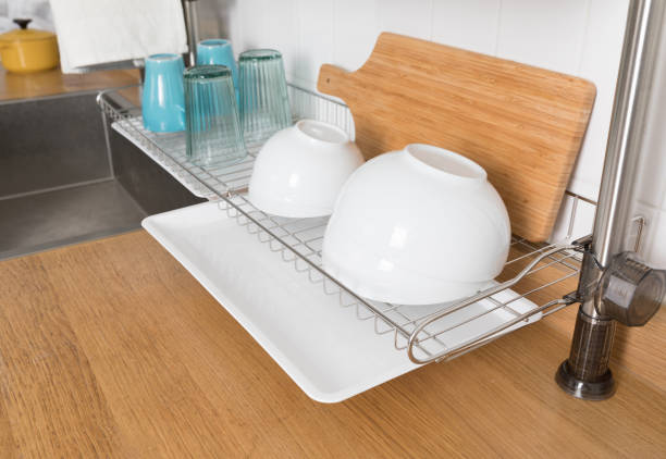istock Clean dishes drying on metal dish rack on light background. Kitchen utensils and dishware on wooden shelf. Kitchen interior background.Text space. 1069622086