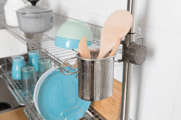 istock Clean dishes drying on metal dish rack on light background. Kitchen utensils and dishware on wooden shelf. Kitchen interior background.Text space. 1069622134