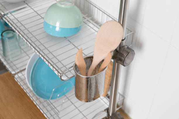 istock Clean dishes drying on metal dish rack on light background. Kitchen utensils and dishware on wooden shelf. Kitchen interior background.Text space. 1069622202
