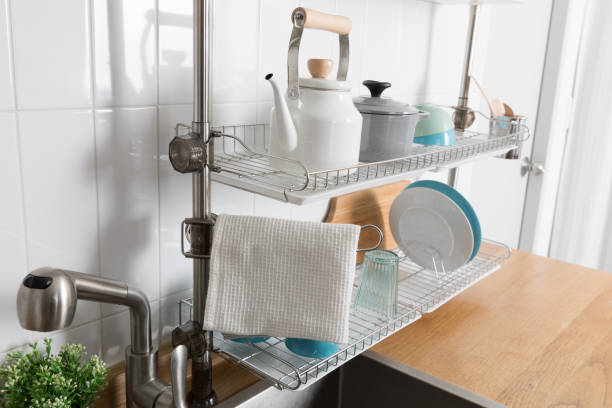 istock Clean dishes drying on metal dish rack on light background. Kitchen utensils and dishware on wooden shelf. Kitchen interior background.Text space. 1069622452