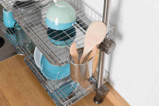 istock Clean dishes drying on metal dish rack on light background. Kitchen utensils and dishware on wooden shelf. Kitchen interior background.Text space. 1069622652