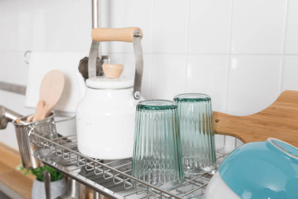 istock Clean dishes drying on metal dish rack on light background. Kitchen utensils and dishware on wooden shelf. Kitchen interior background.Text space. 1069622772