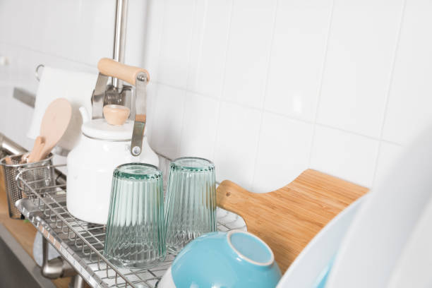 istock Clean dishes drying on metal dish rack on light background. Kitchen utensils and dishware on wooden shelf. Kitchen interior background.Text space. 1069622782