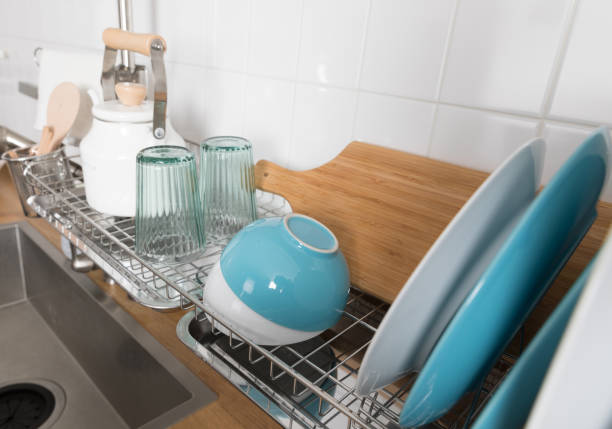 istock Clean dishes drying on metal dish rack on light background. Kitchen utensils and dishware on wooden shelf. Kitchen interior background.Text space. 1069622796
