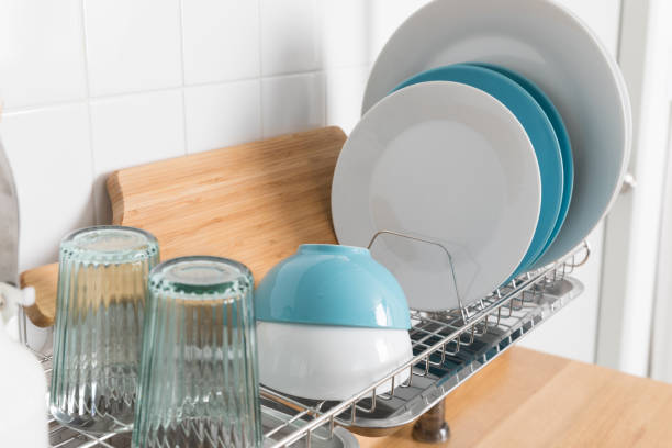 istock Clean dishes drying on metal dish rack on light background. Kitchen utensils and dishware on wooden shelf. Kitchen interior background.Text space. 1069622806