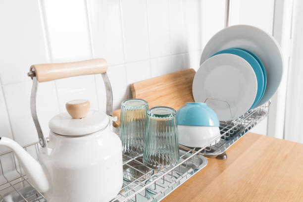 istock Clean dishes drying on metal dish rack on light background. Kitchen utensils and dishware on wooden shelf. Kitchen interior background.Text space. 1069622820
