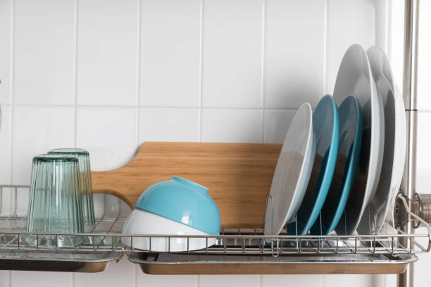istock Clean dishes drying on metal dish rack on light background. Kitchen utensils and dishware on wooden shelf. Kitchen interior background.Text space. 1069622826