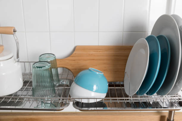istock Clean dishes drying on metal dish rack on light background. Kitchen utensils and dishware on wooden shelf. Kitchen interior background.Text space. 1069622838