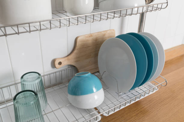 istock Clean dishes drying on metal dish rack on light background. Kitchen utensils and dishware on wooden shelf. Kitchen interior background.Text space. 1069622864