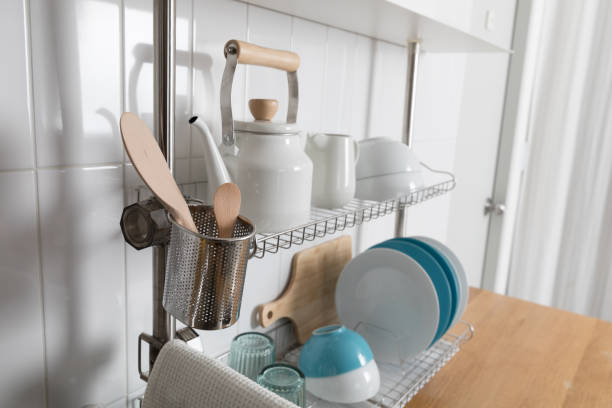 istock Clean dishes drying on metal dish rack on light background. Kitchen utensils and dishware on wooden shelf. Kitchen interior background.Text space. 1069622910