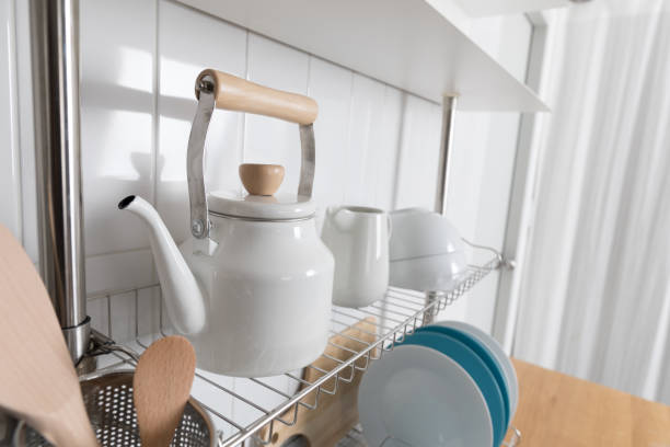 istock Clean dishes drying on metal dish rack on light background. Kitchen utensils and dishware on wooden shelf. Kitchen interior background.Text space. 1069622914