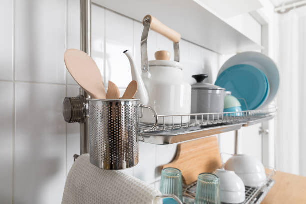 istock Clean dishes drying on metal dish rack on light background. Kitchen utensils and dishware on wooden shelf. Kitchen interior background.Text space. 1069624986