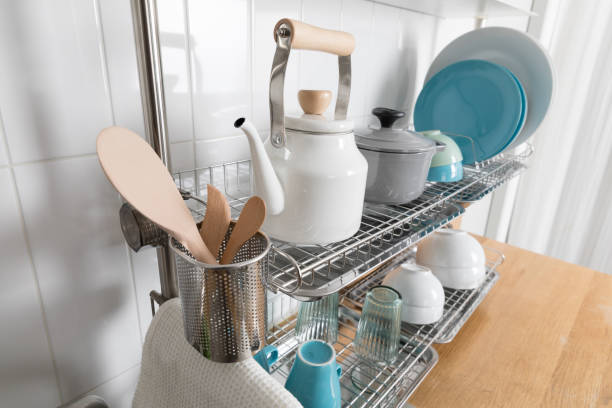 istock Clean dishes drying on metal dish rack on light background. Kitchen utensils and dishware on wooden shelf. Kitchen interior background.Text space. 1069625176