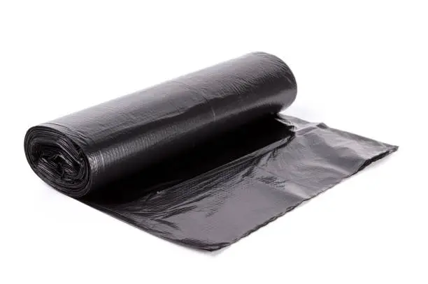 Photo of Black roll of plastic garbage bags isolated on white background