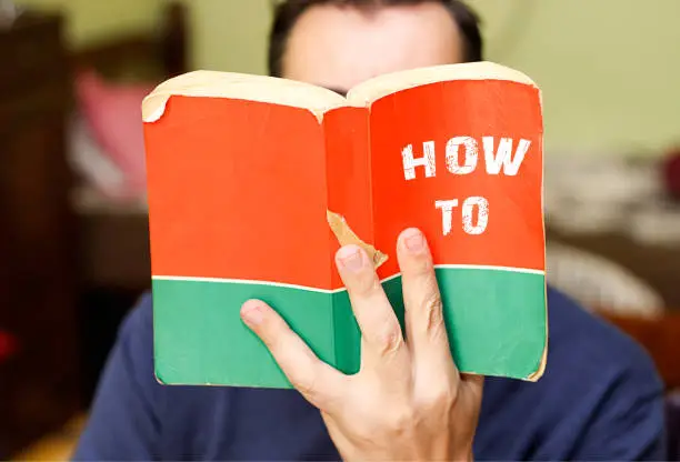 person holding and read in from book with text title, how to