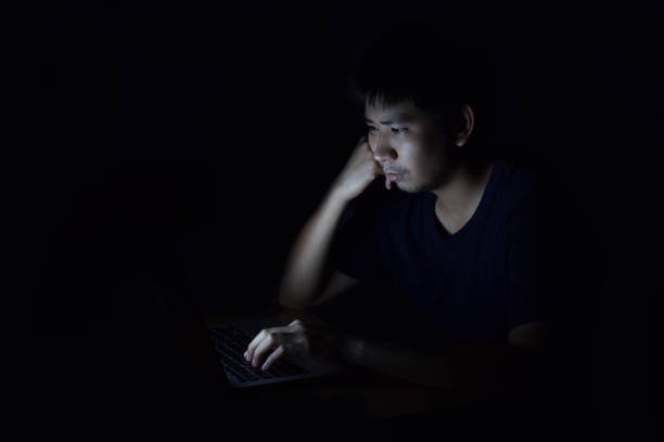 istock Asian man using laptop in the black dark room and show thinking something on his face 1069643586