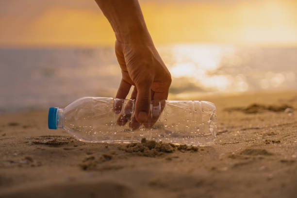 istock Hand Keep  cleanup  the Plastic bottle on beach at the sunset scene 1069645536