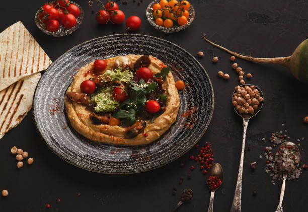 istock Hummus with vegetables and seafood on black background 1069661454