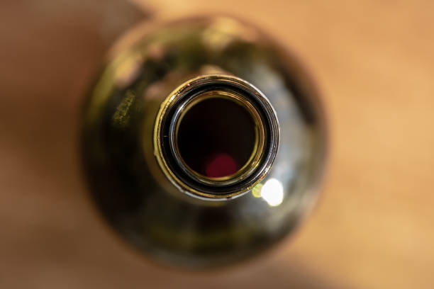 Detail of the neck of the glass bottle can be seen, showing the green bottle on an out of coms dinner table.