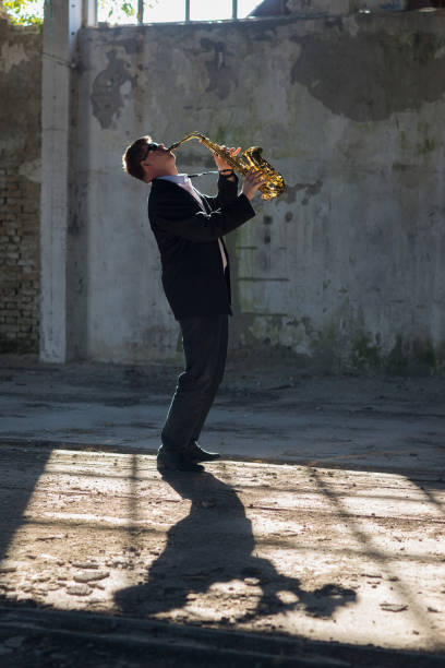 istock Young musician playing on the saxophone in the abandoned building 1069674806
