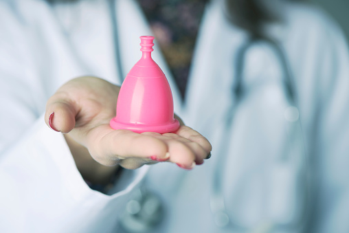 médico mujer mostrando una copa menstrual rosa photo
