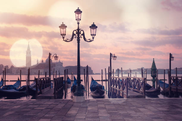istock Venice classic sunrise view with gondolas on the waves and bokeh lights 1069679070