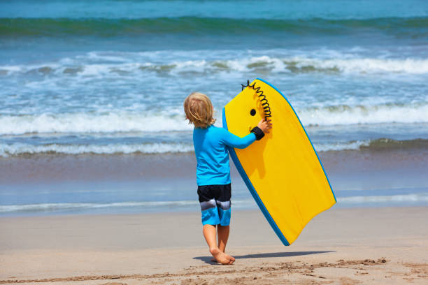 istock Little surfer run with bodyboard on sea beach 1069679306