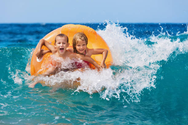 istock Happy kids have fun in sea surf on beach. 1069681876